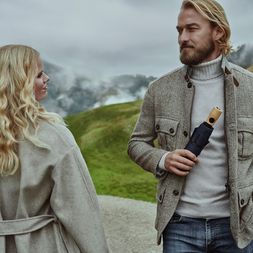 Knirps Timber Duomatic Knirps Timber Regenschirm in Schwarz wird von einem Mann gehalten, im Hintergrund ist eine blonde Frau mit Locken zu sehen